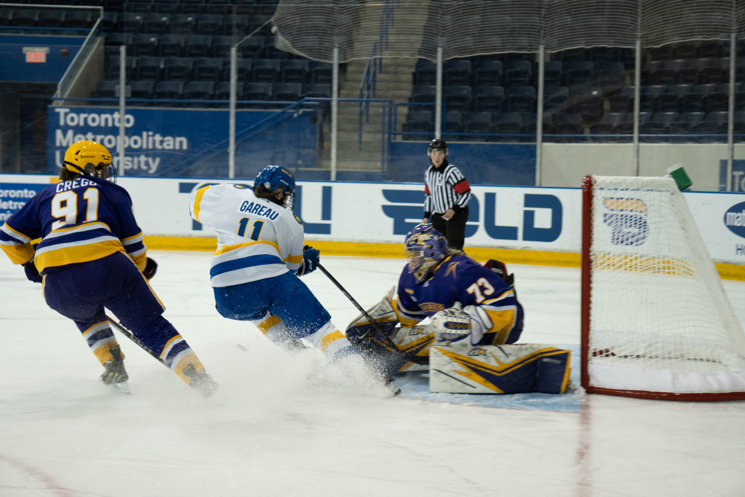 TMU Bold women's hockey player Gaby Gareau sends a spray of snow into the goaltender as she stops with the puck