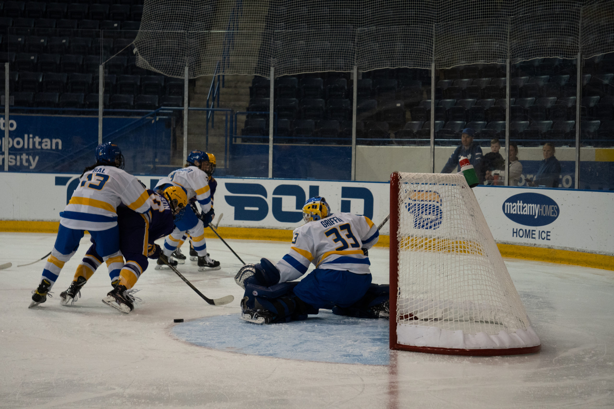 TMU Bold goaltender Lauren Griffin makes a kick save as players hurry towards the net