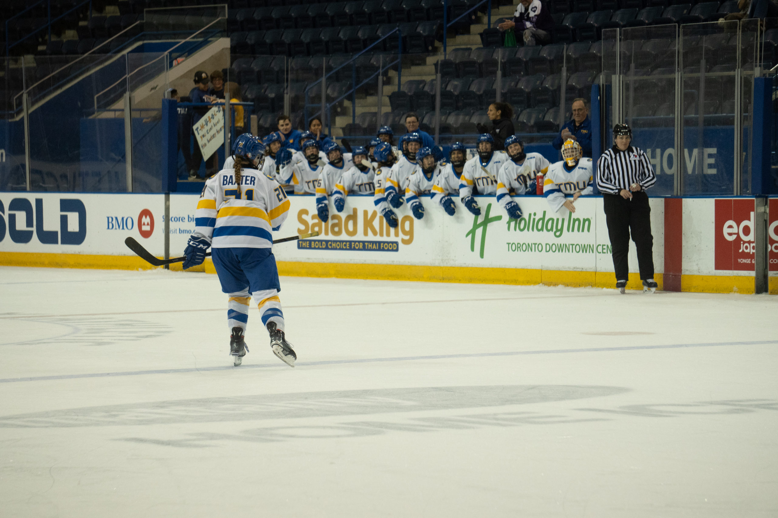 Emily Baxter skates back towards the bench where her teammates are smiling