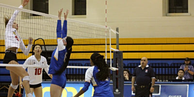 TMU Bold women's volleyball players attempt to defend and block a hit by a Guelph Gryphons player