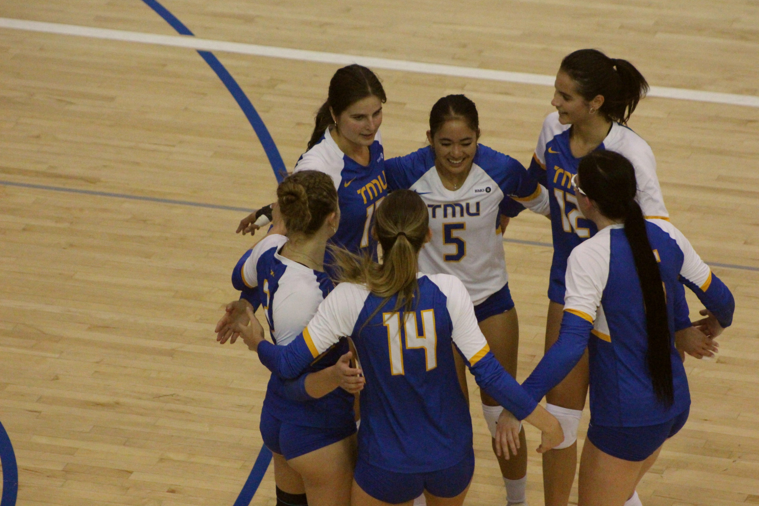 TMU Bold women's volleyball players gather after a point