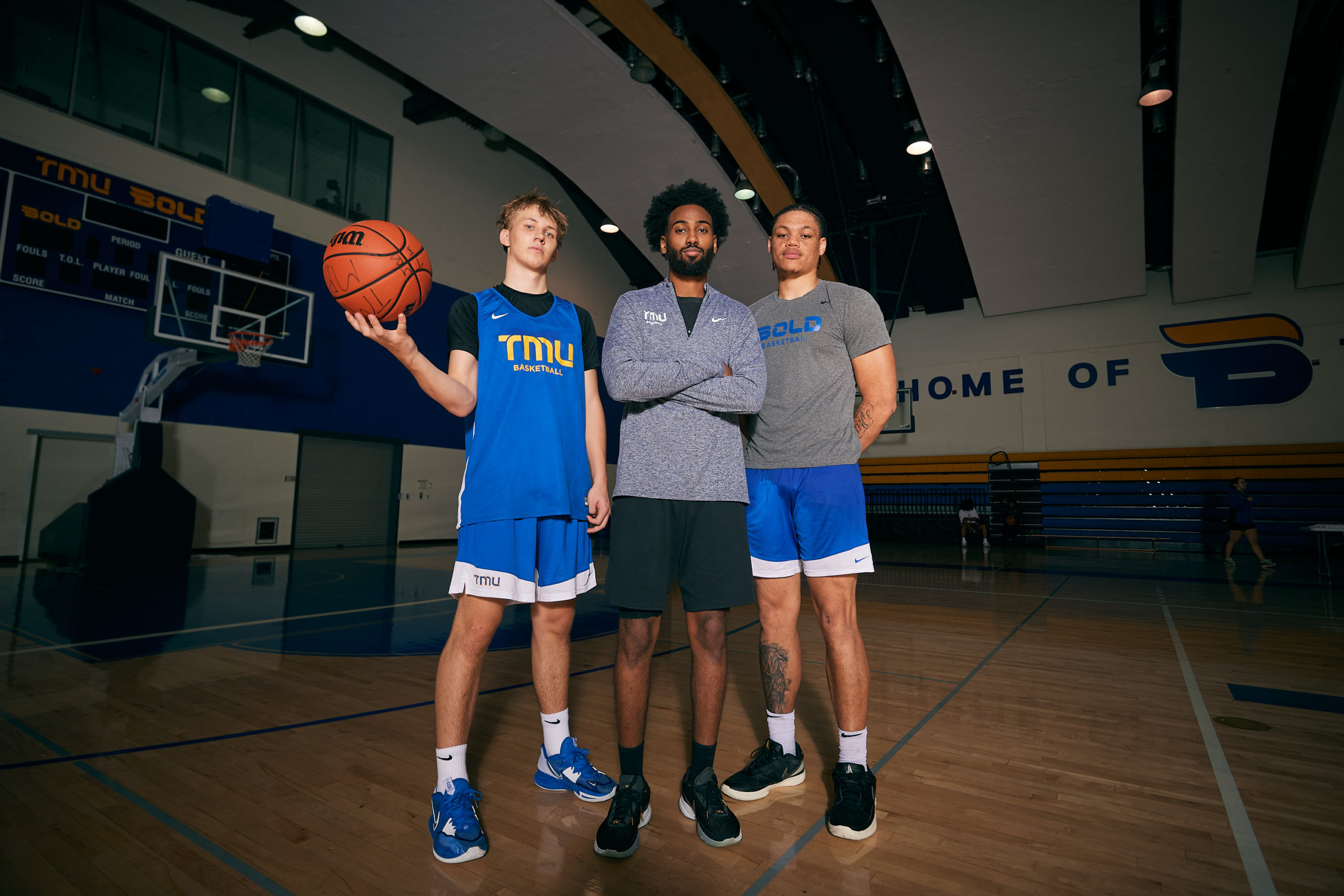 Moustapha Youssouf, Kevin Toth and Aaron Rhooms pose for a photo on the MAC basketball court