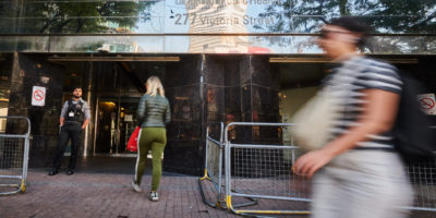 Pedestrians walk past a street level view of a safe injection site in Toronto.