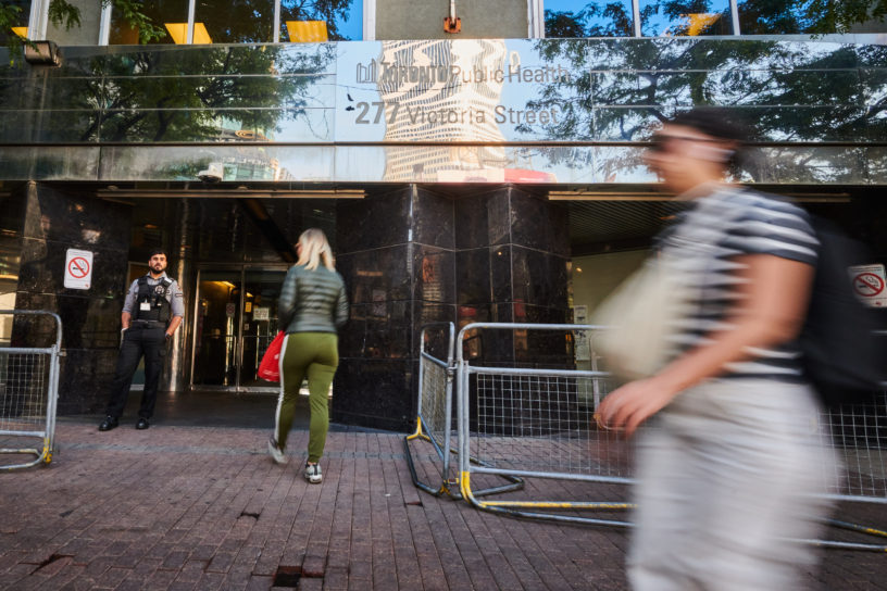 Pedestrians walk past a street level view of a safe injection site in Toronto.