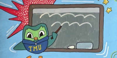 An illustration of Duo the Duolingo mascot wearing a blue TMU sweater pointing a stick towards a grey chalkboard.