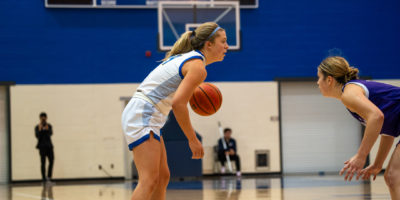 TMU Bold women's basketball player Kaillie Hall dribbles a basketball as a Bishop's Gaiters player approaches her