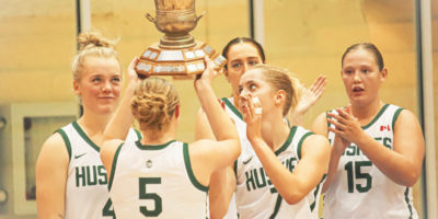 Saskatchewan Huskies guard Gage Grassick lifts the Darcel Wright Memorial Classic trophy over her head with her teammates