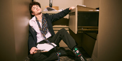 An office worker leans against a filing cabinet, looking tired.