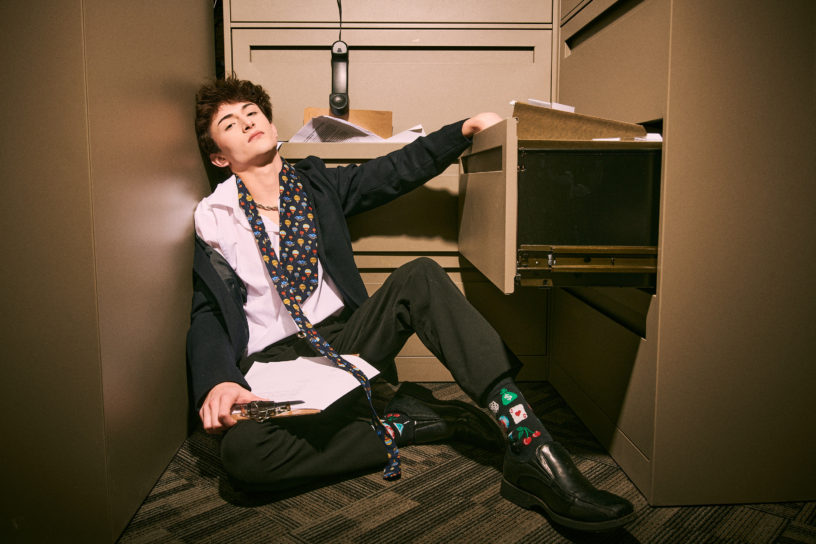 An office worker leans against a filing cabinet, looking tired.