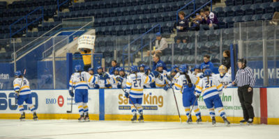 TMU women's hockey team high fiving players as they skate by.