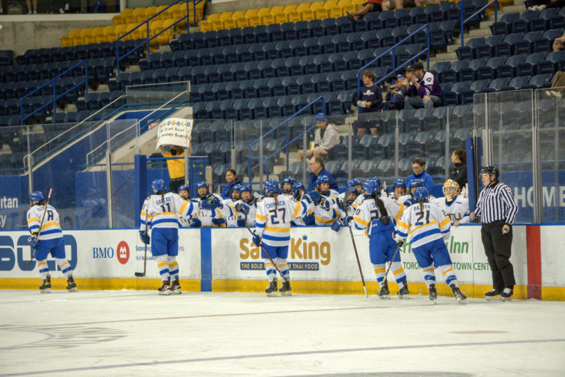 TMU women's hockey team high fiving players as they skate by.