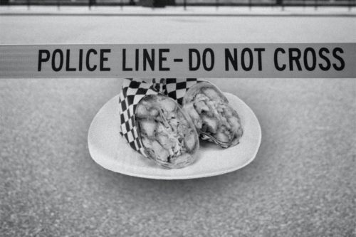 A black and white photo illustration of a Metro whiskey chicken wrap on a plate on the pavement. The two wraps are surrounded by police "do not cross" tape