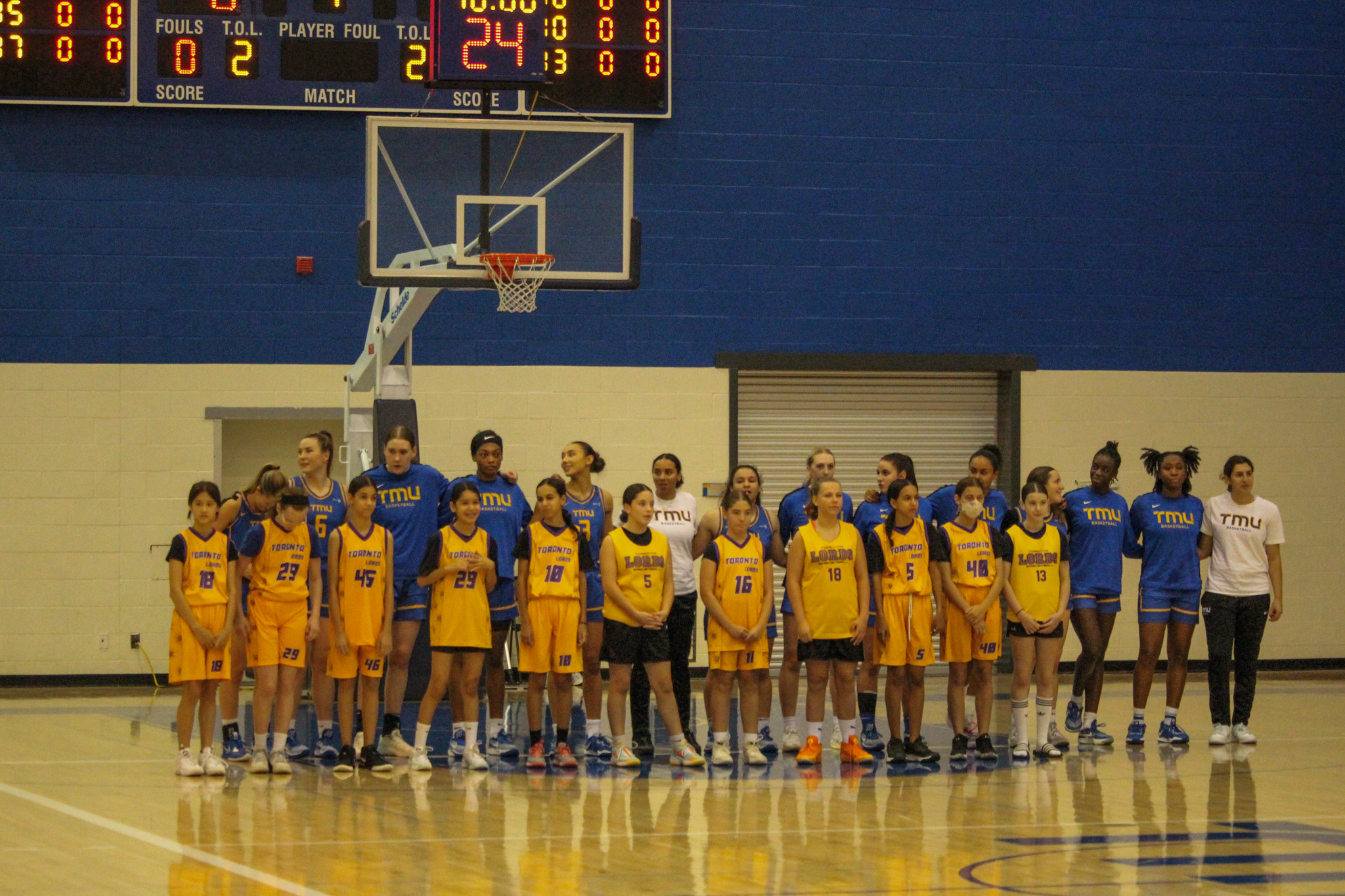 The TMU Bold women's basketball team lined up to sing the national anthem with mascots by their side