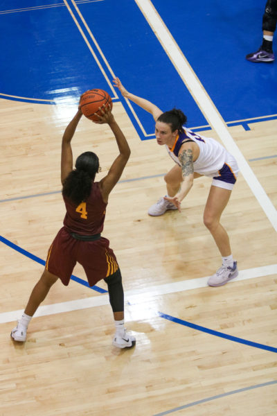 A Concordia Stingers player holds the ball in the air over the head of a Laurier Golden Hawks player