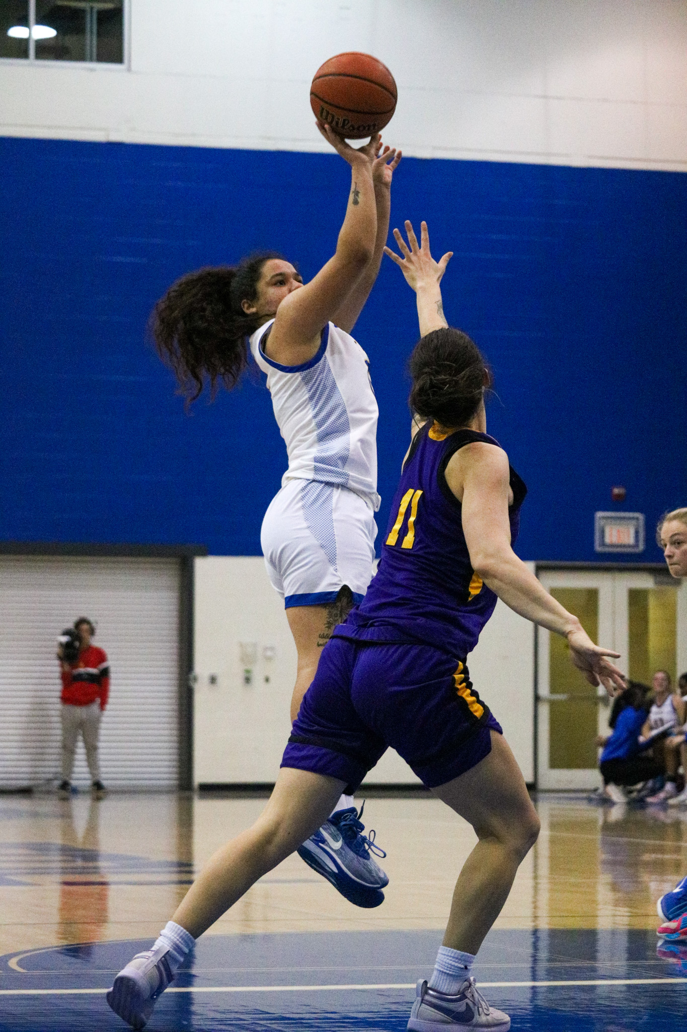 Kait Nichols shoots a basketball from the air over a Laurier Golden Hawks player