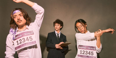 A photo composite of two prospective empoyees wearing marathon bibs, with an employer in the centre holding a clipboard.