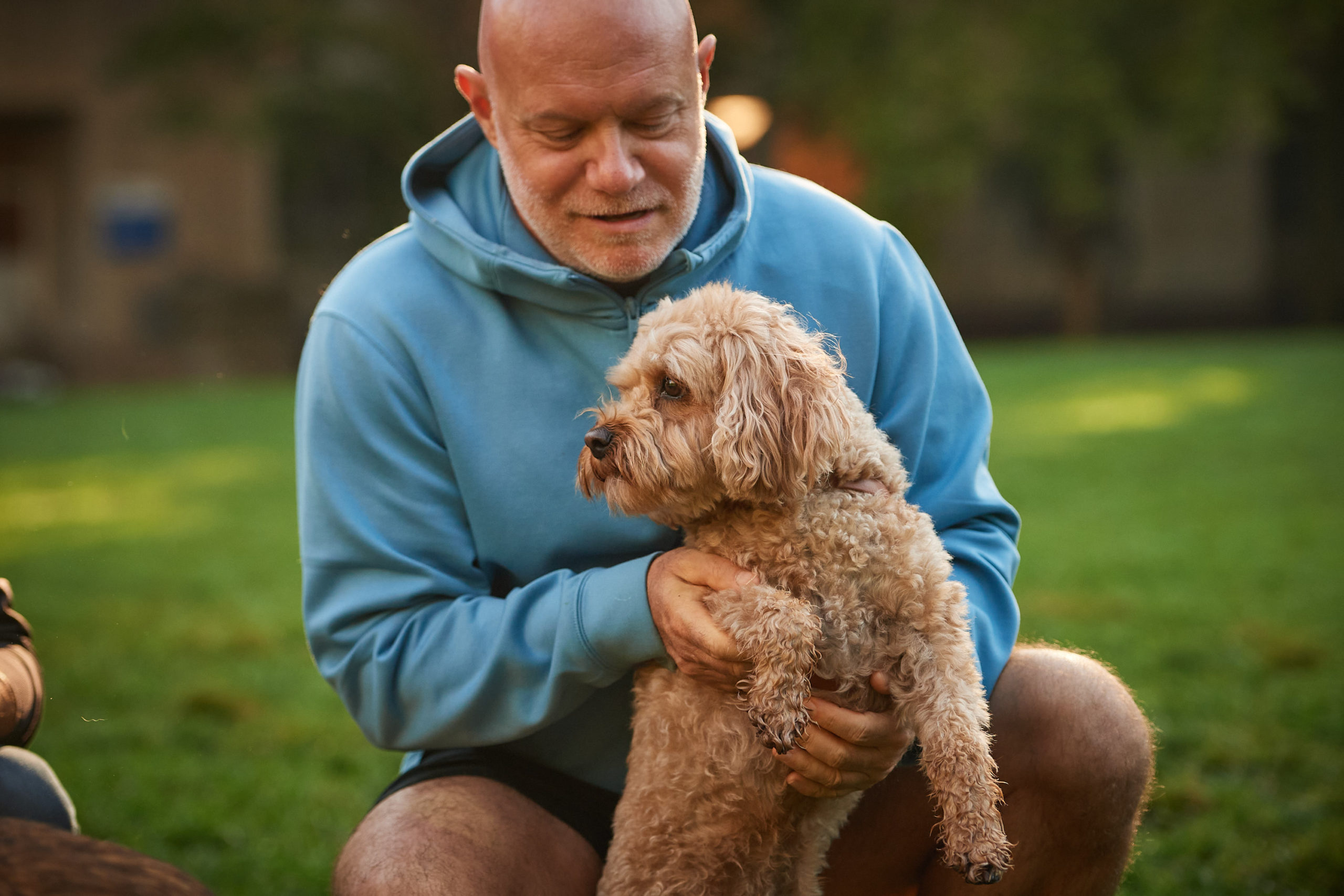 A close up of a dog owner holding up their dog.