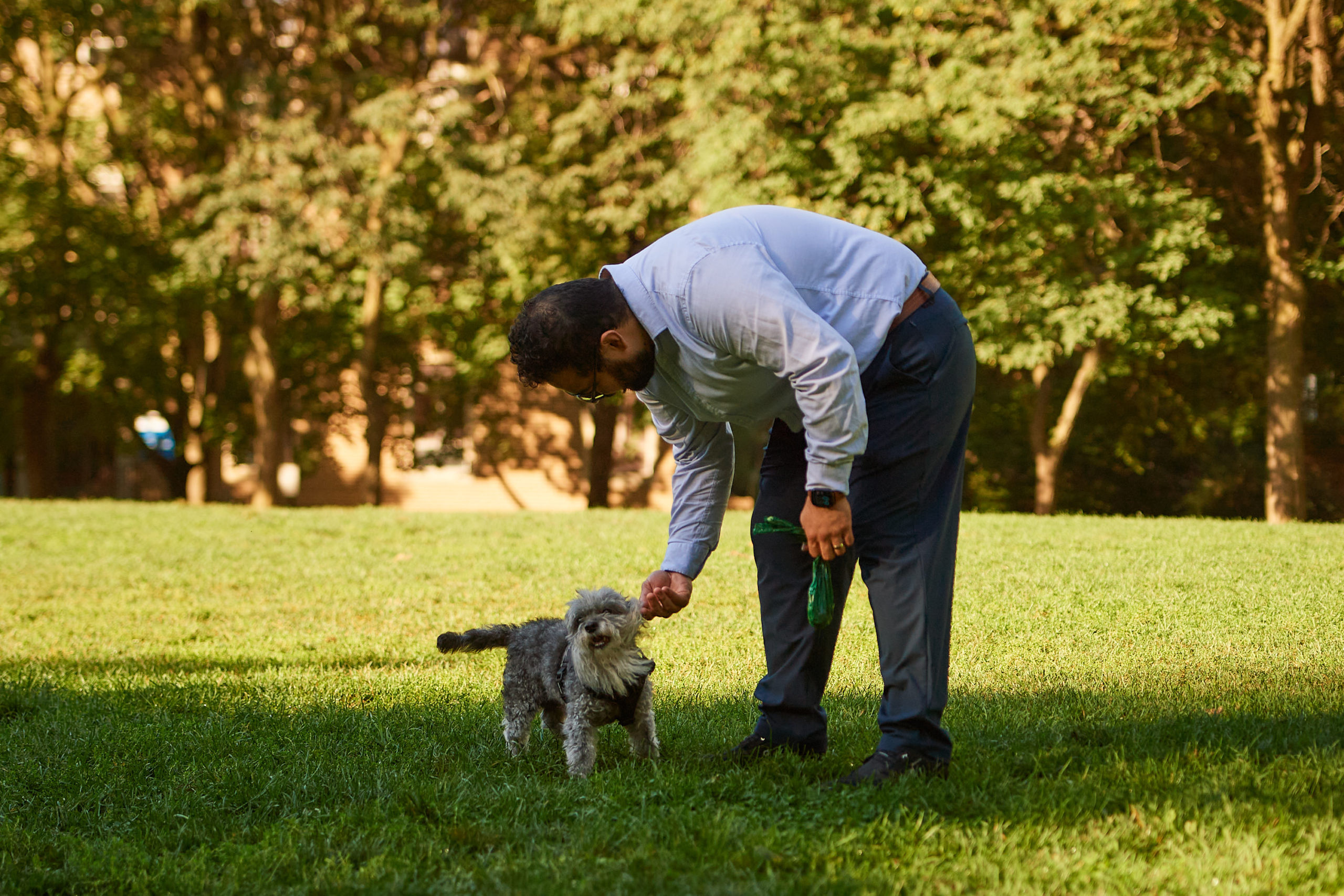 A dog owner bends over to scratch their dogs ear.