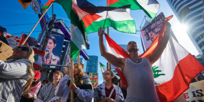 A group of protestors carry flags and signs as they march.