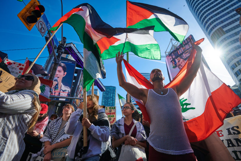 A group of protestors carry flags and signs as they march.