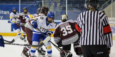 Kayla Kondo skates past the Ottawa Gee-Gees goalie at the end of a play. A ref stands by the net