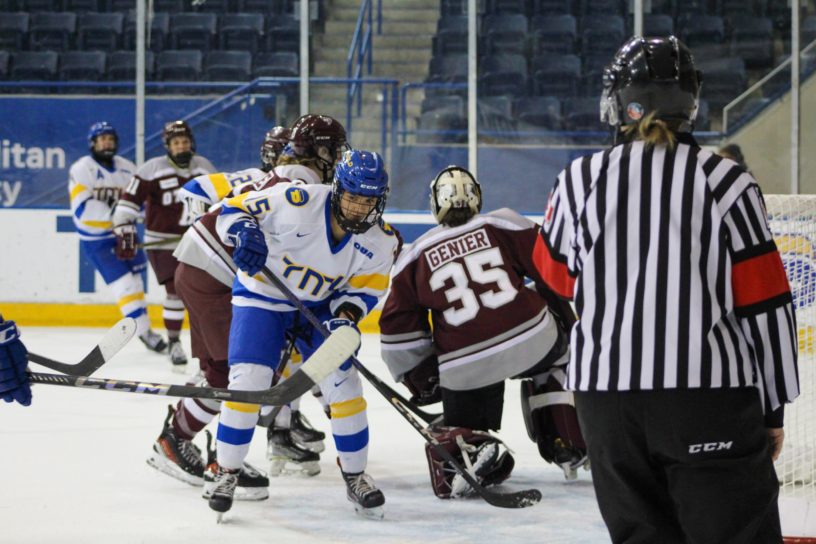 Kayla Kondo skates past the Ottawa Gee-Gees goalie at the end of a play. A ref stands by the net