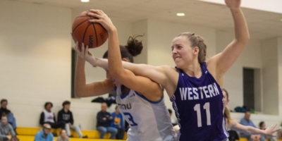 A Western Mustangs player reaches for a basketball in Hailey Franco-DeRyck's hands