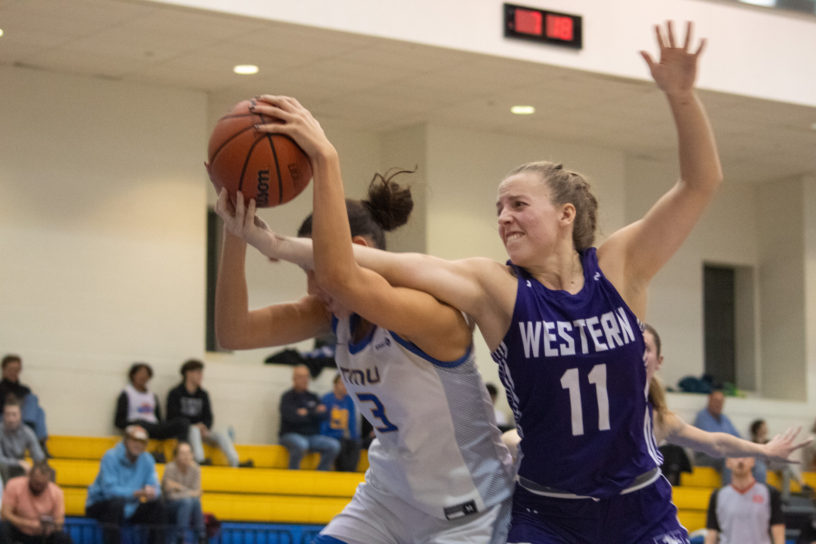 A Western Mustangs player reaches for a basketball in Hailey Franco-DeRyck's hands