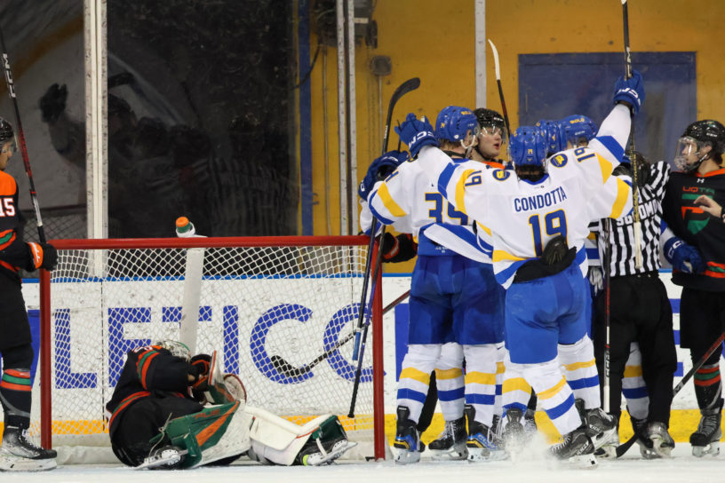 TMU Bold players celebrate a goal as the UQTR goalie gets up off the ice in his net