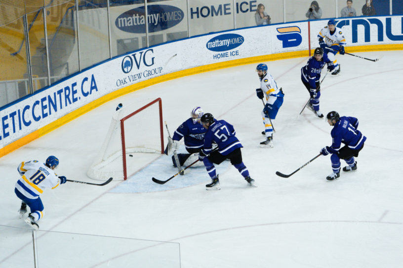 Kevin Gursoy shoots a puck into the net from the side of the net