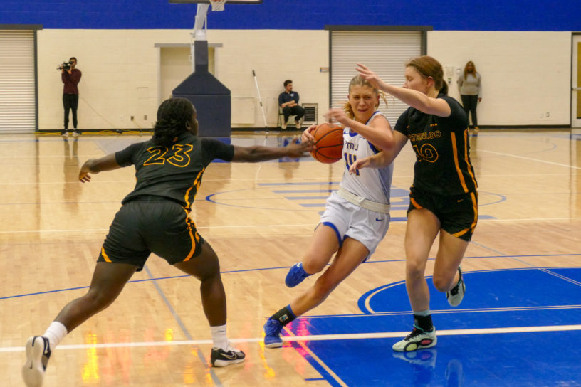 Kaillie Hall battles through two defenders grabbing at the basketball