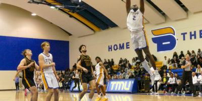 Galand Okeugo dunks a basketball as TMU and Waterloo players watch