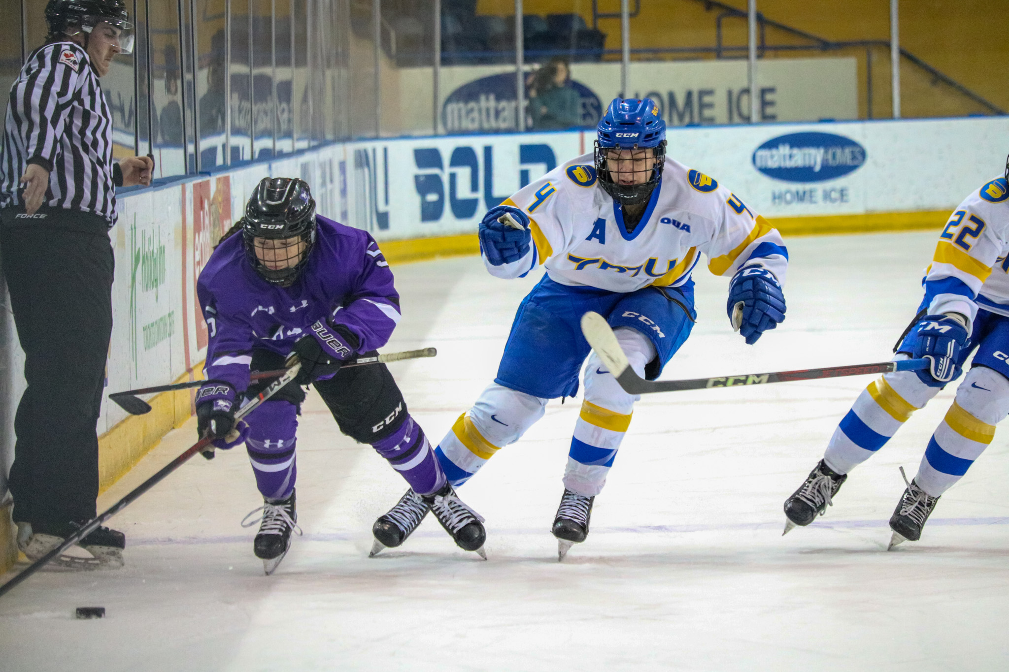 A Western player dragging the puck and stealing the stick of a TMU player