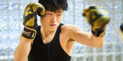 A member of the TMU Muay Thai Club practices his punching with black and gold gloves