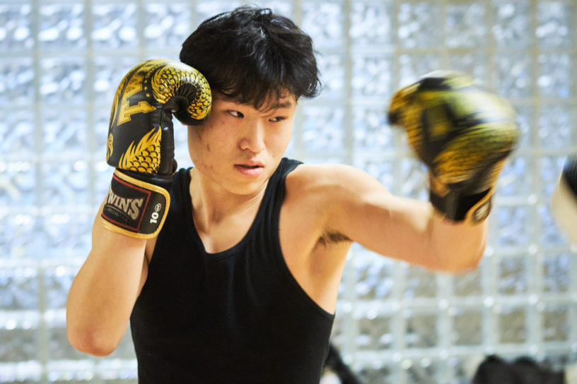 A member of the TMU Muay Thai Club practices his punching with black and gold gloves