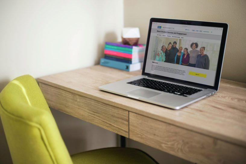 A laptop sits on a desk, open to the Black Student Success and Engagement page on the Toronto Metropolitan University website.