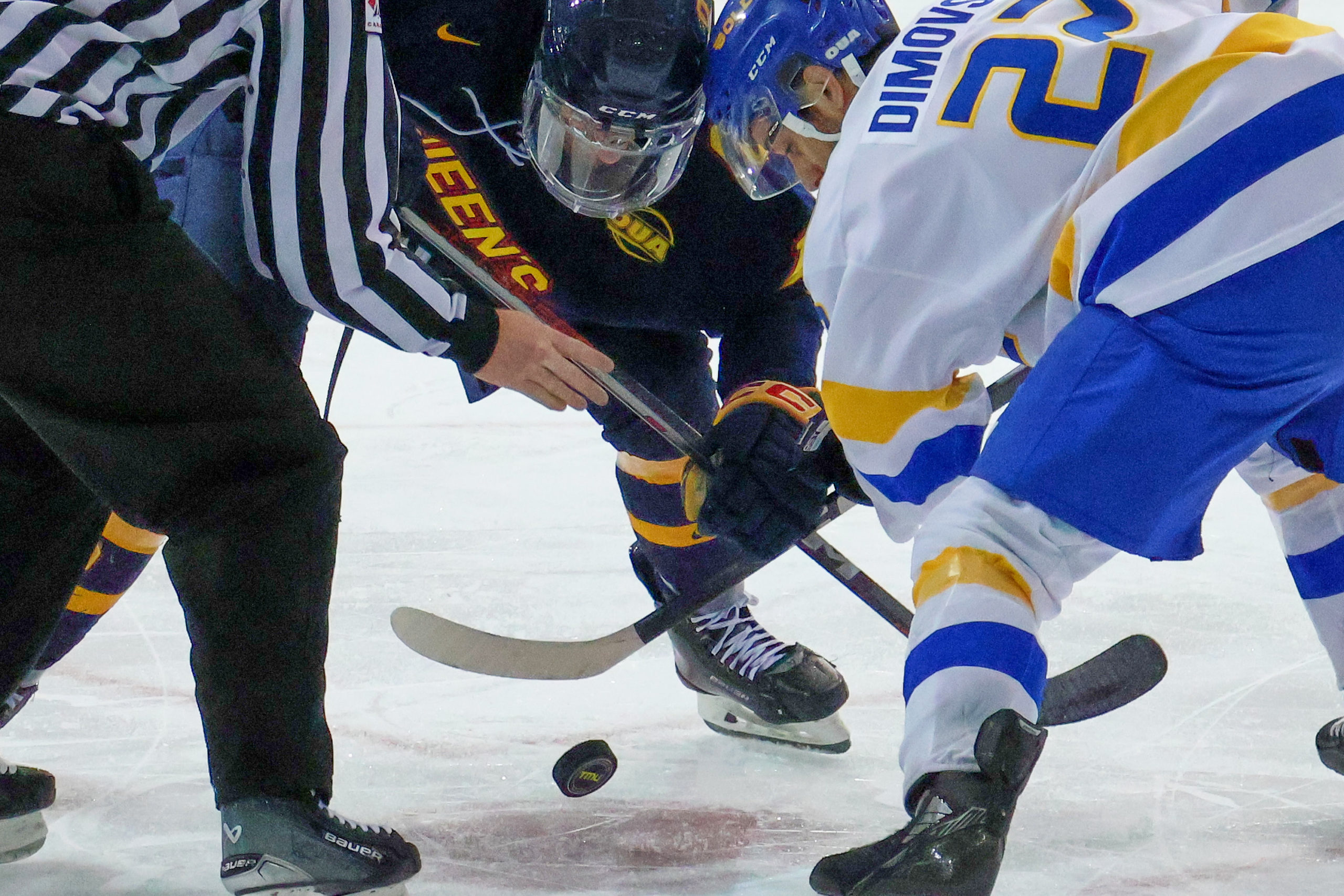 A TMU player and a Queen's player take a face off