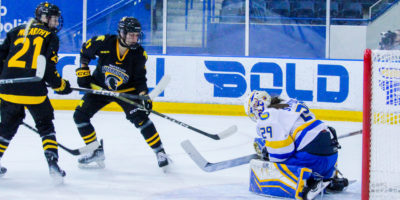 Alexia Stratos makes a save as two Waterloo Warriors approach her net