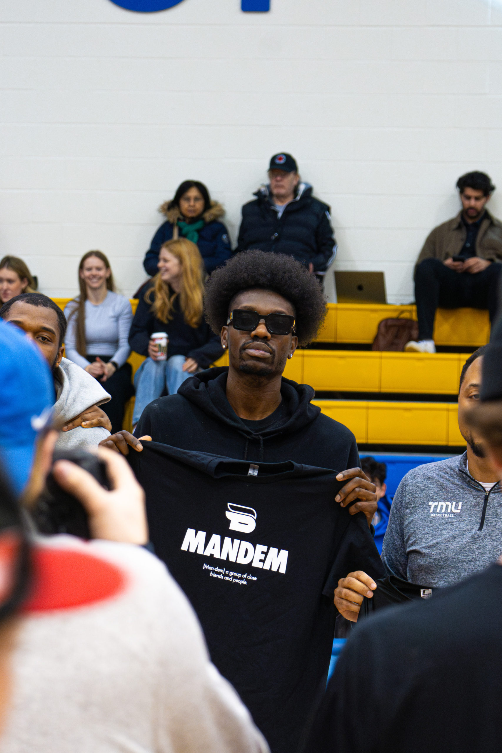 Chris Boucher holds up a TMU basketball "mandem" shirt