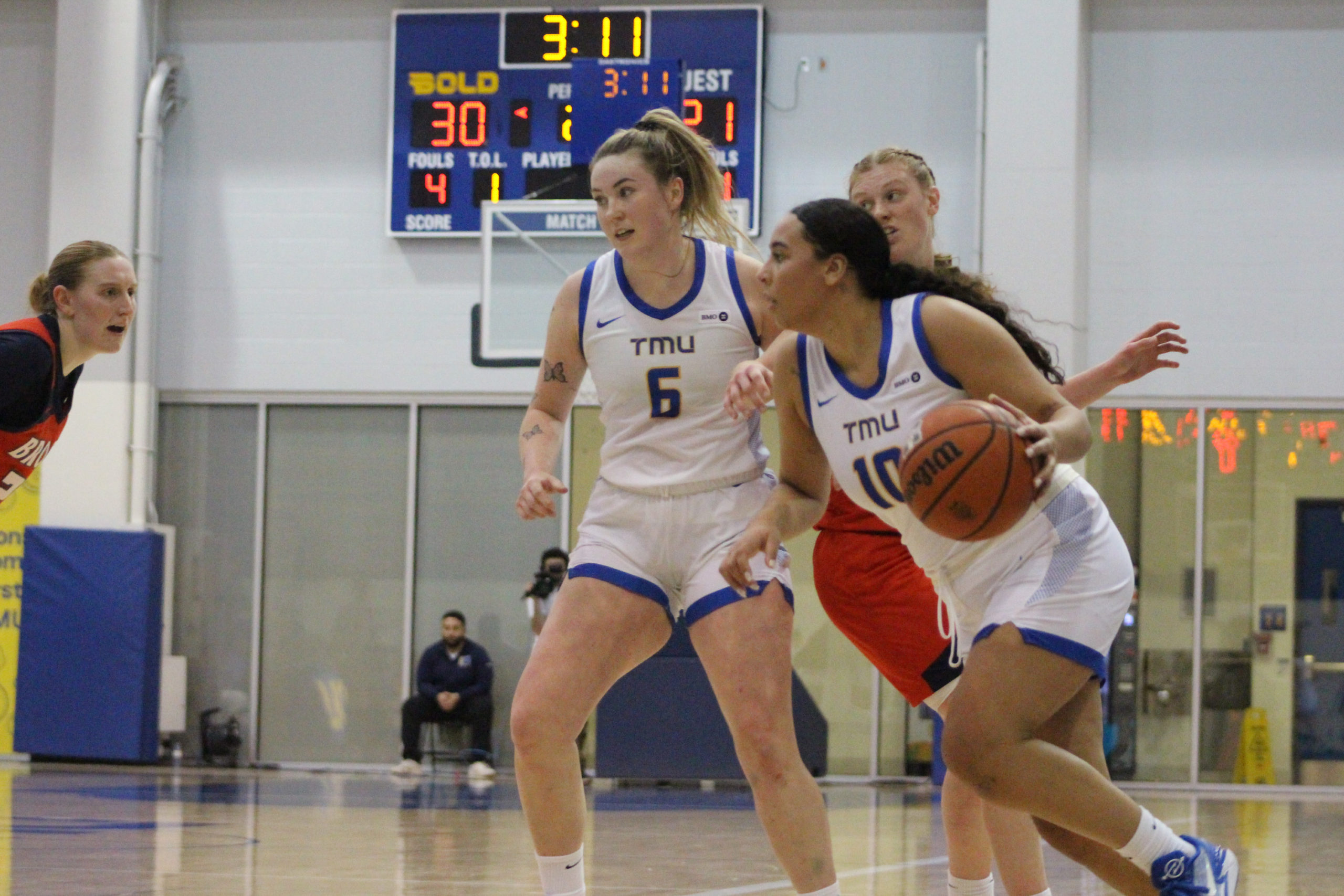 Jayme Foreman dribbles a basketball past Haley Fedick and a Badgers defender