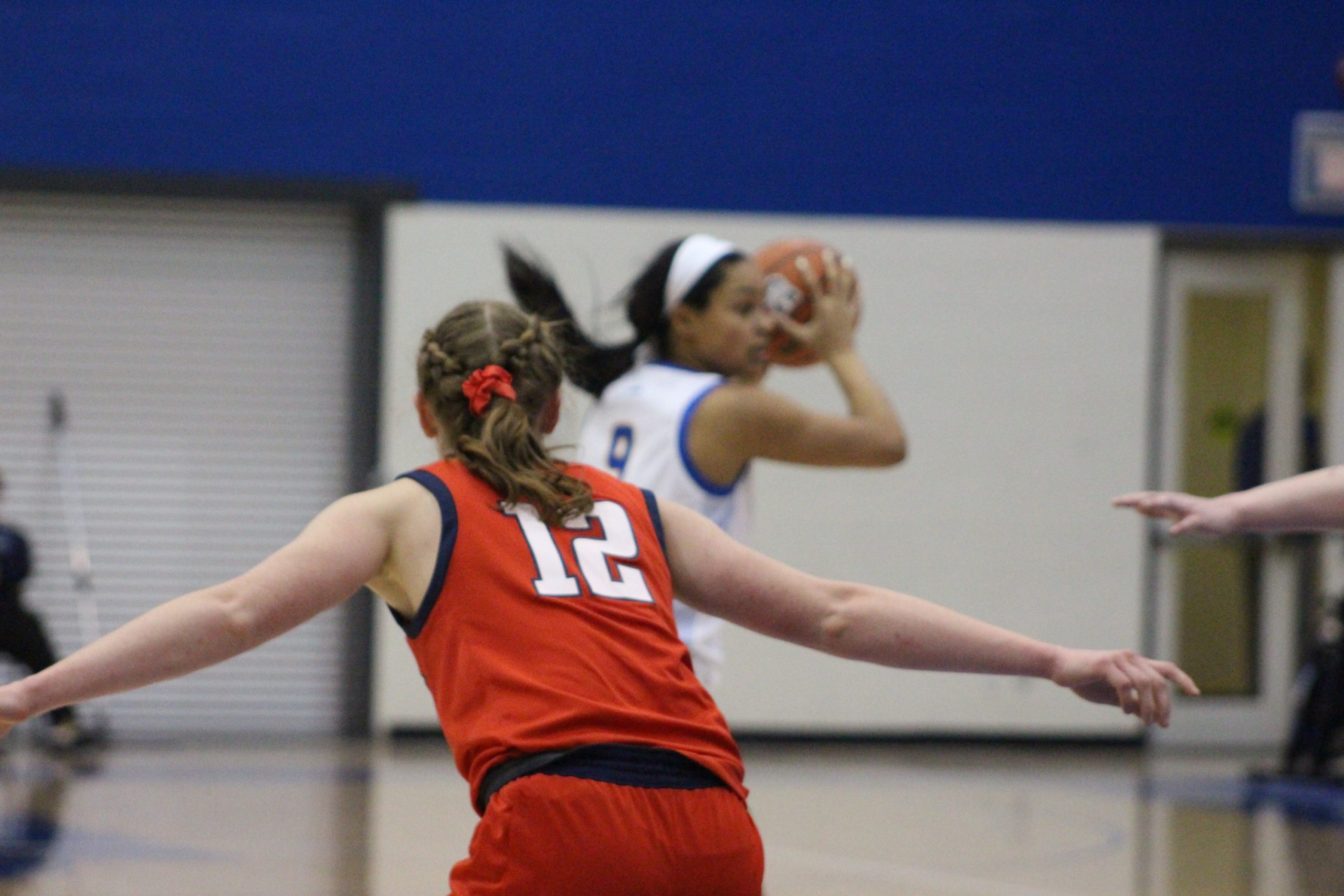 A Brock Badgers player in a number 12 jersey spreads her arms as Callie Wright holds the basketball at her head