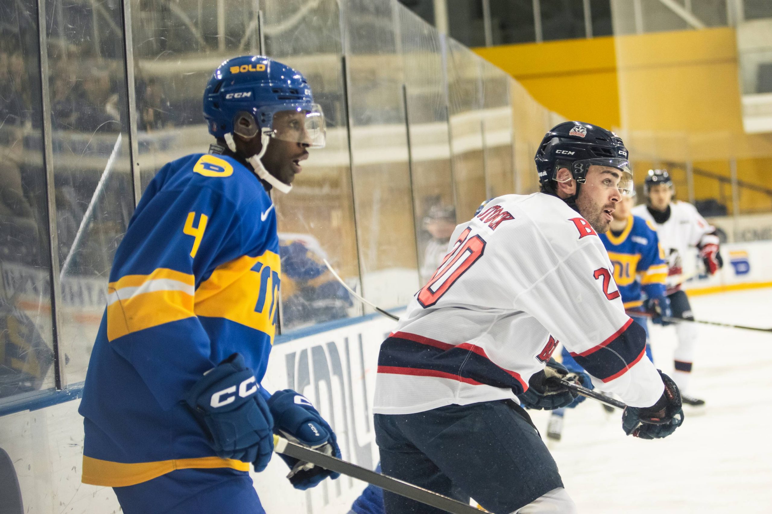 Matt Barnes and a Brock player stare ahead at the puck