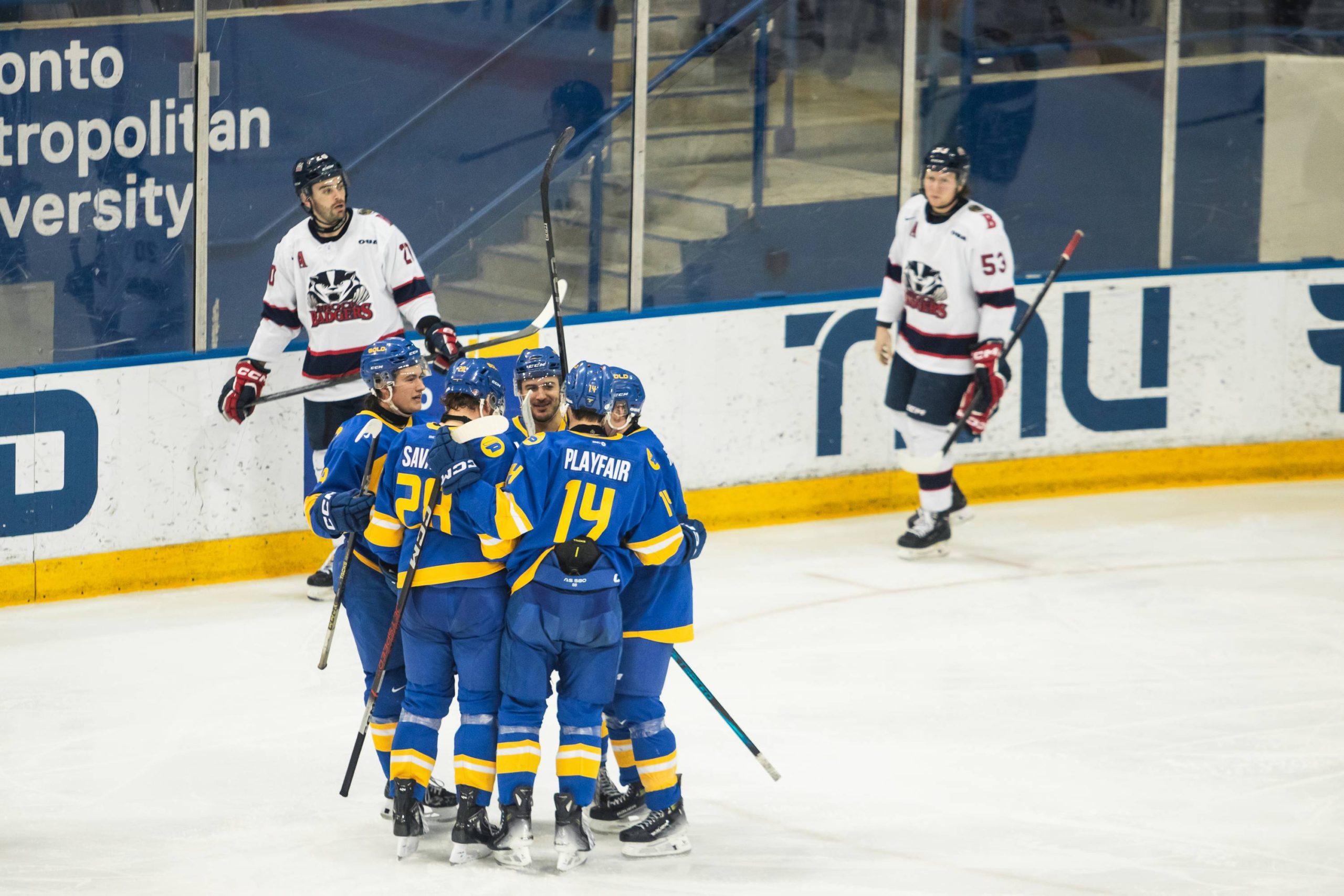 TMU Bold players celebrate a goal witha group hug against the Brock Badgers