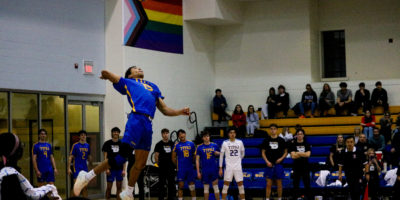 Jacob Walker serves a ball from the air as his team watches from the bench