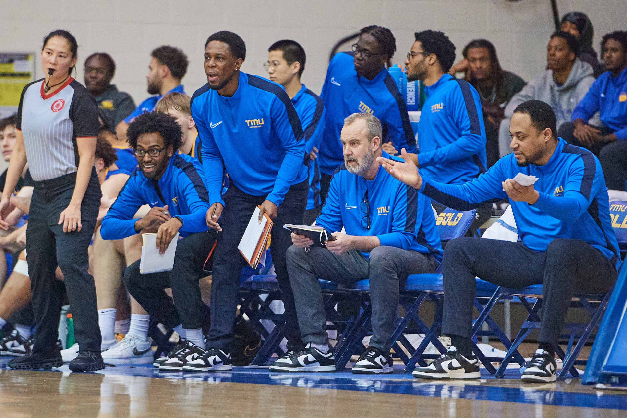 The TMU Bold bench reacts to a play on the court