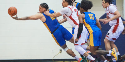 Aaron Rhooms reaches from a crowd of players to catch a basketball