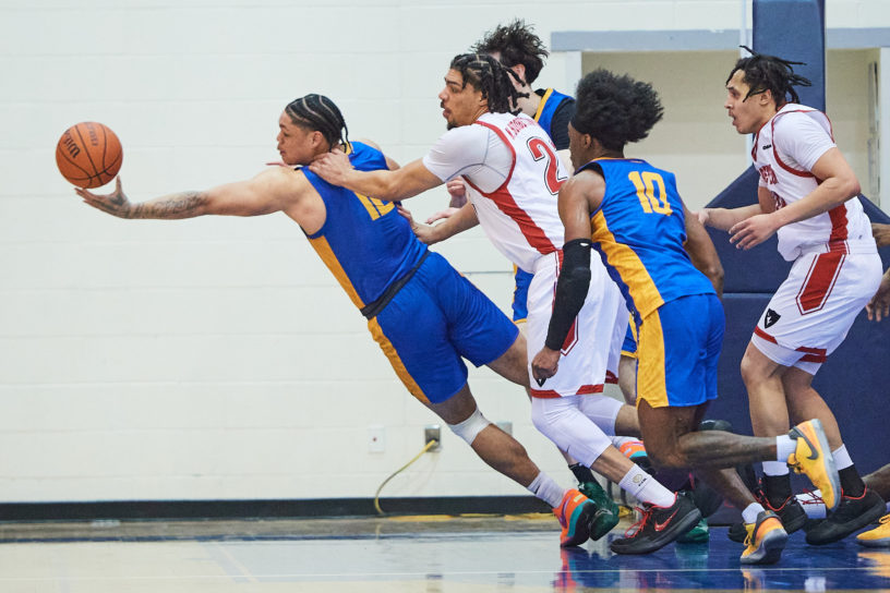 Aaron Rhooms reaches from a crowd of players to catch a basketball