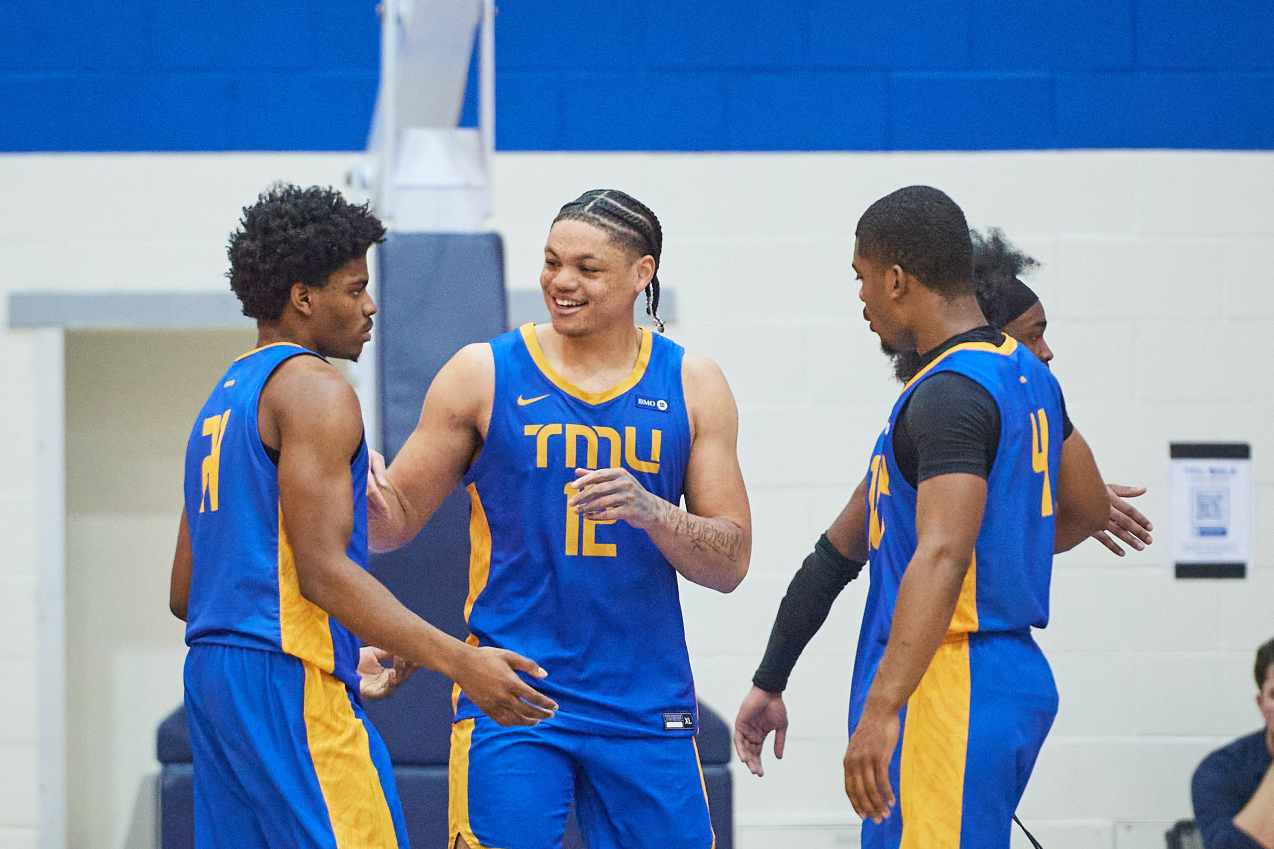 Aaron Rhooms, Gabriel Gutsmore and Maxime Louis-Jean smile as they gather on the court