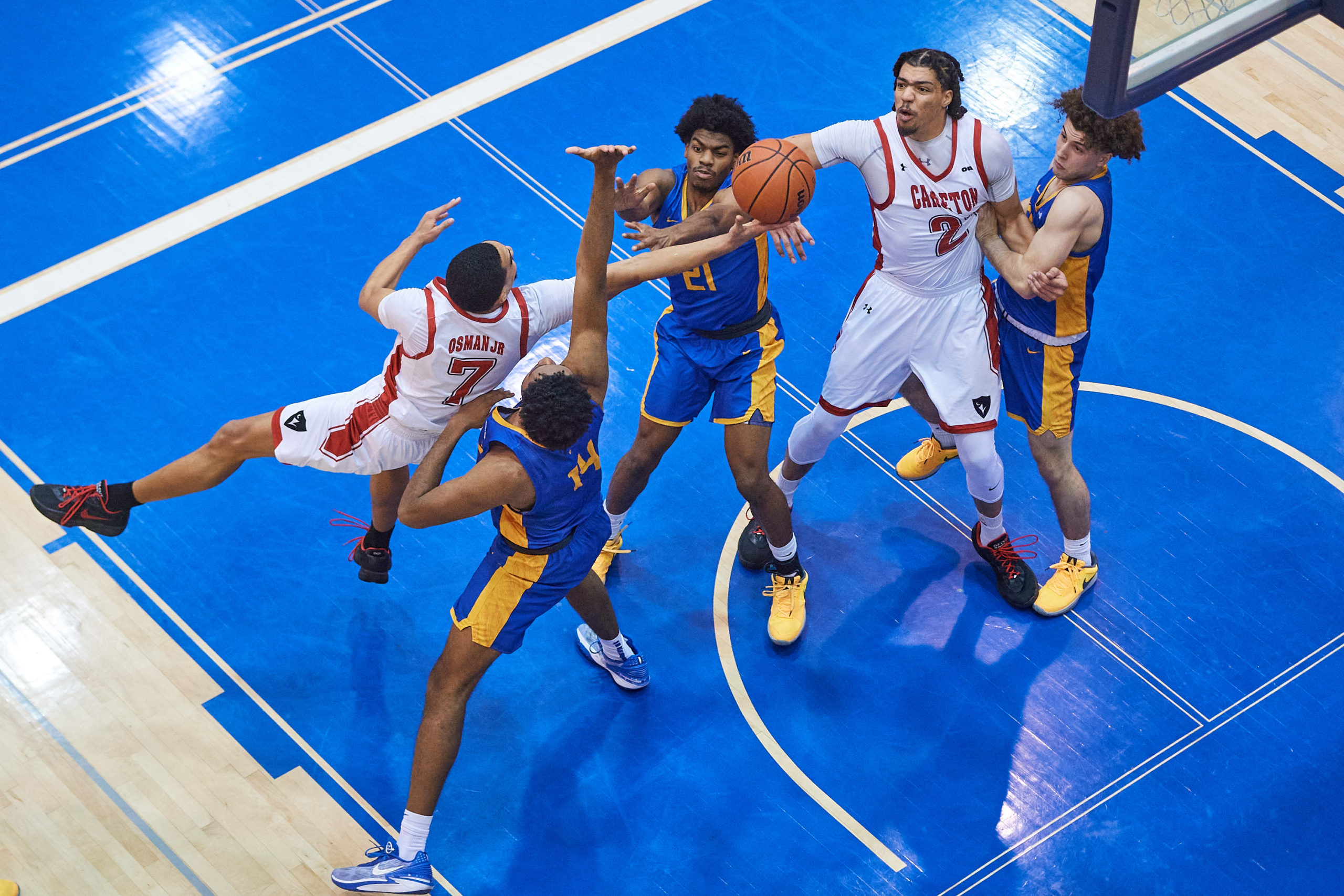 TMU and Carleton basketball players battle for a loose ball in the air