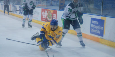 Matthew Kinash handling the puck as he's falling to the ground